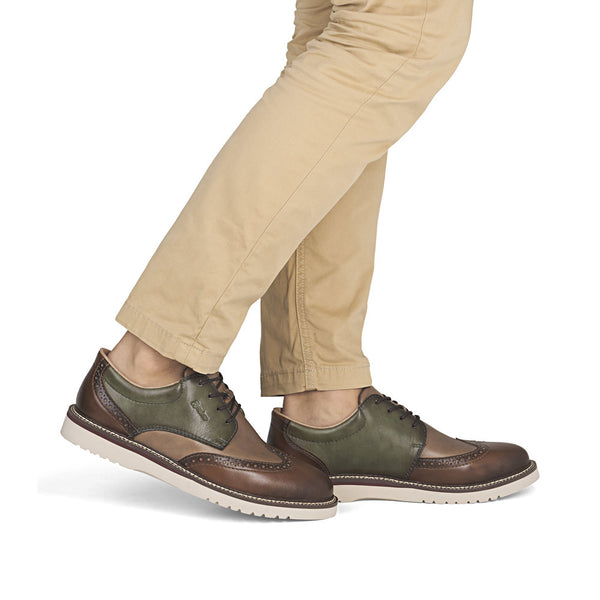 Brown and green leather shoes worn with beige pants on a white background