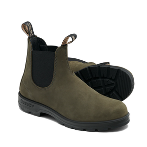 Pair of green Chelsea boots with black soles on a white background