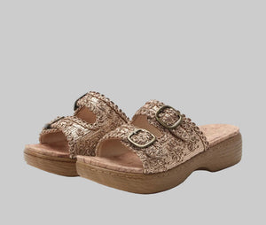 Pair of gold sandals with decorative straps on a white background