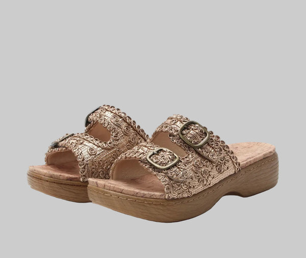 Pair of gold sandals with decorative straps on a white background