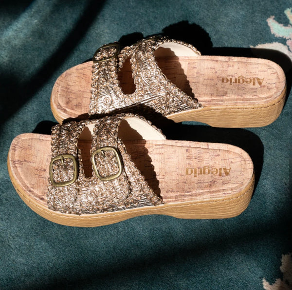 Pair of gold sandals with cork sole on a dark surface