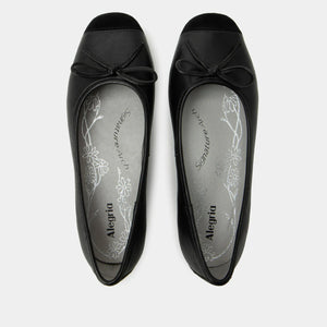 Black flat shoes with a bow on a white background